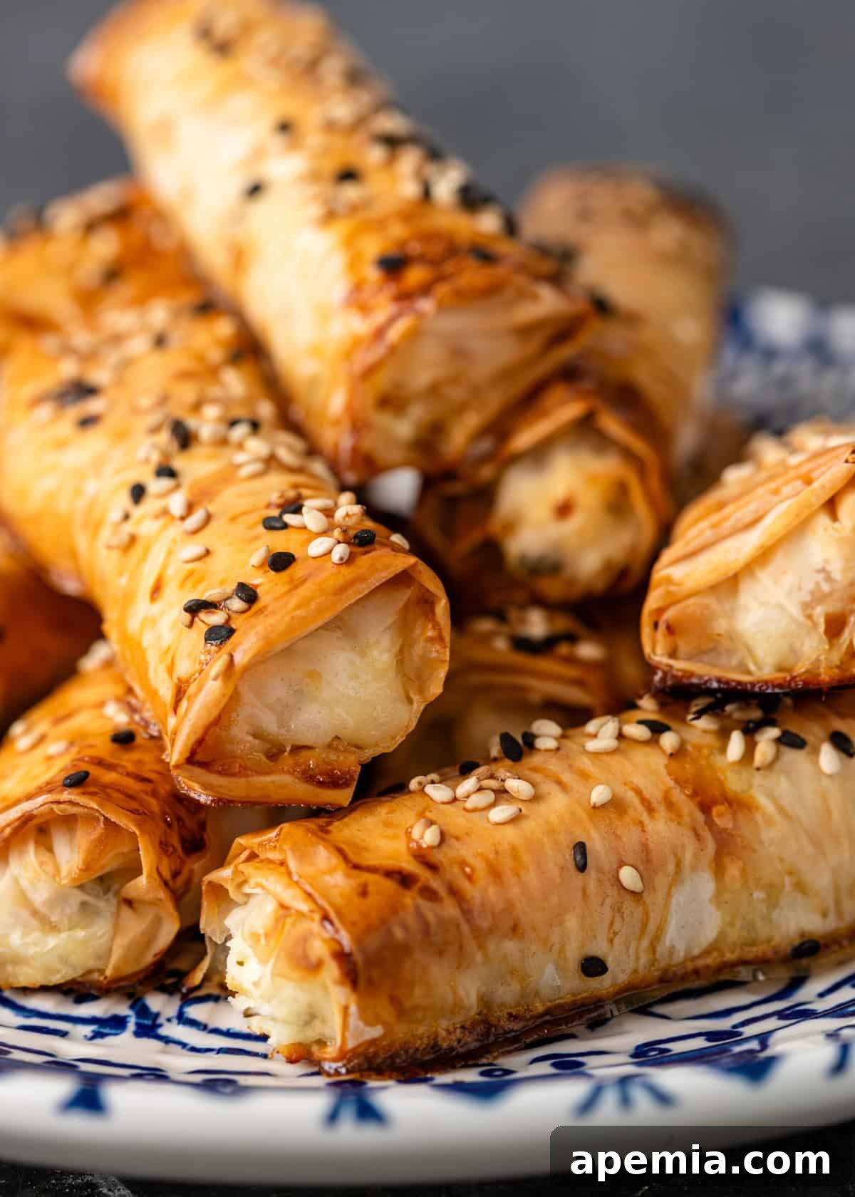 Golden Feta Börek Rolls 12 Closeup: a stack of golden Turkish cheese rolls, perfectly baked and sprinkled with seeds, ready for serving.