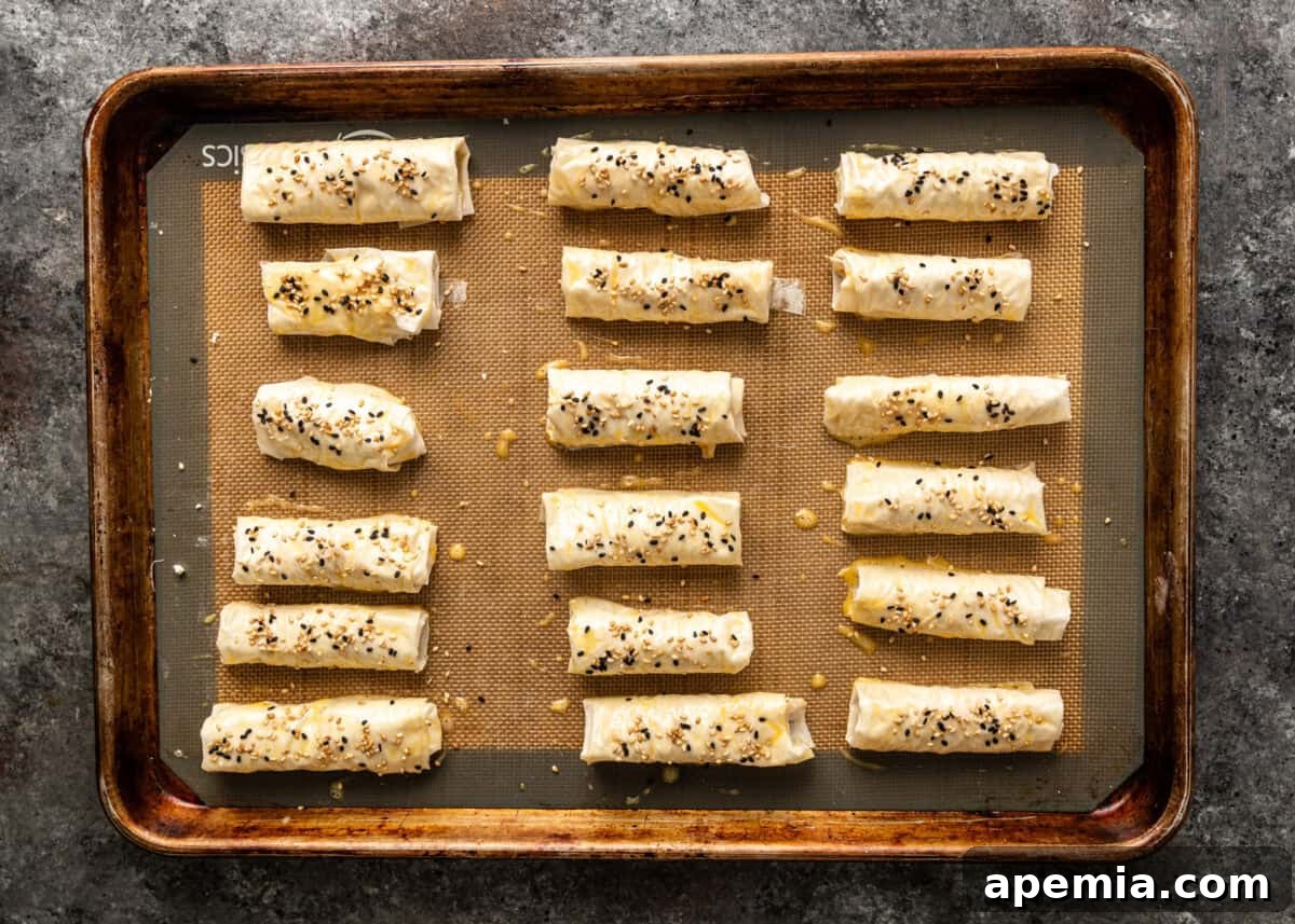 Golden Feta Börek Rolls 9 Overhead: Sigara Borek arranged on a baking sheet before being brushed with egg wash and baked.