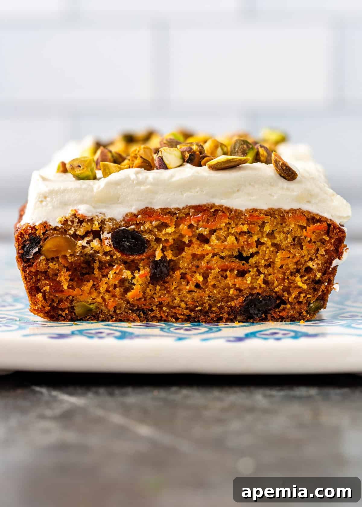 side view carrot cake with cream cheese frosting and chopped nuts on top