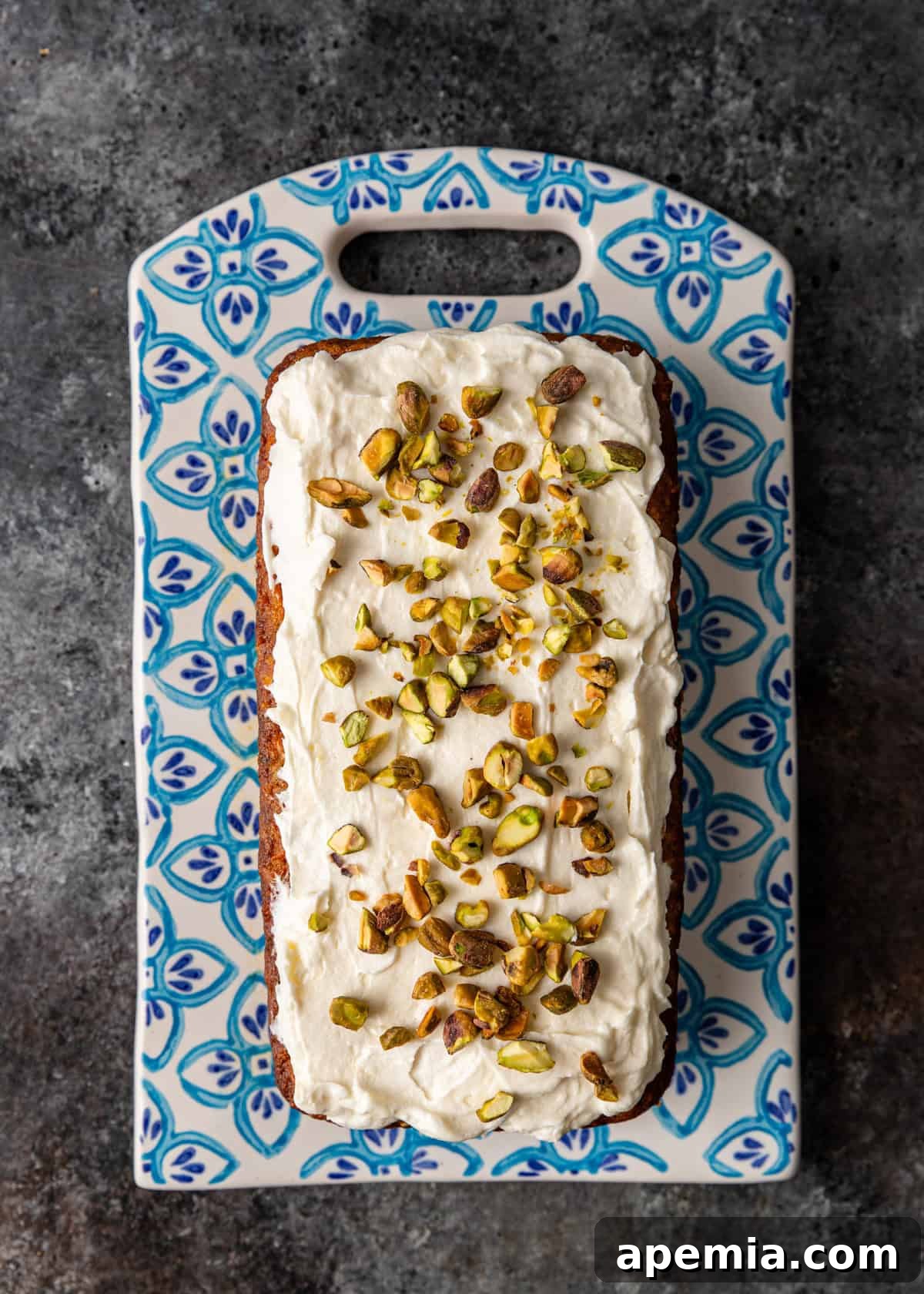 overhead: carrot cake loaf with frosting and chopped pistachios on top
