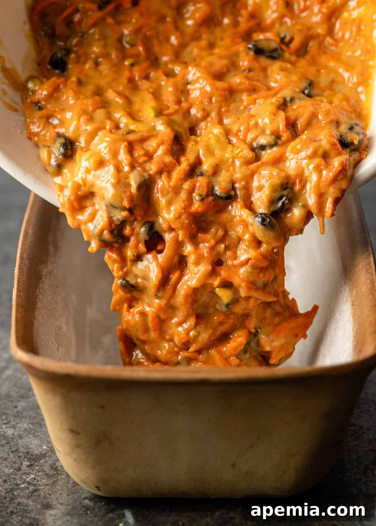 side view: pouring the carrot cake loaf batter into a loaf pan