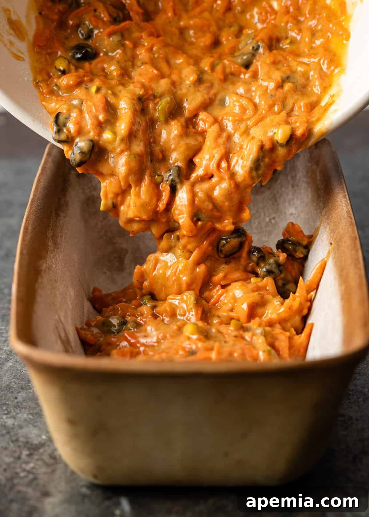 side view: pouring my carrot cake recipe batter into a prepped loaf pan