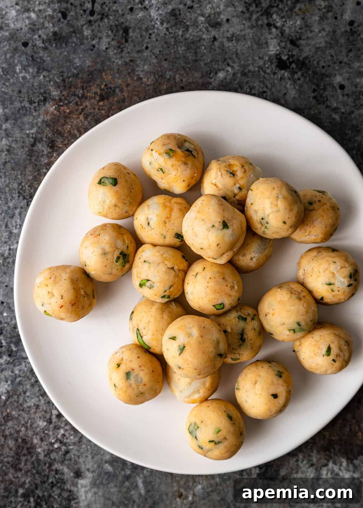 Overhead view of crispy potato patties on a white plate before frying
