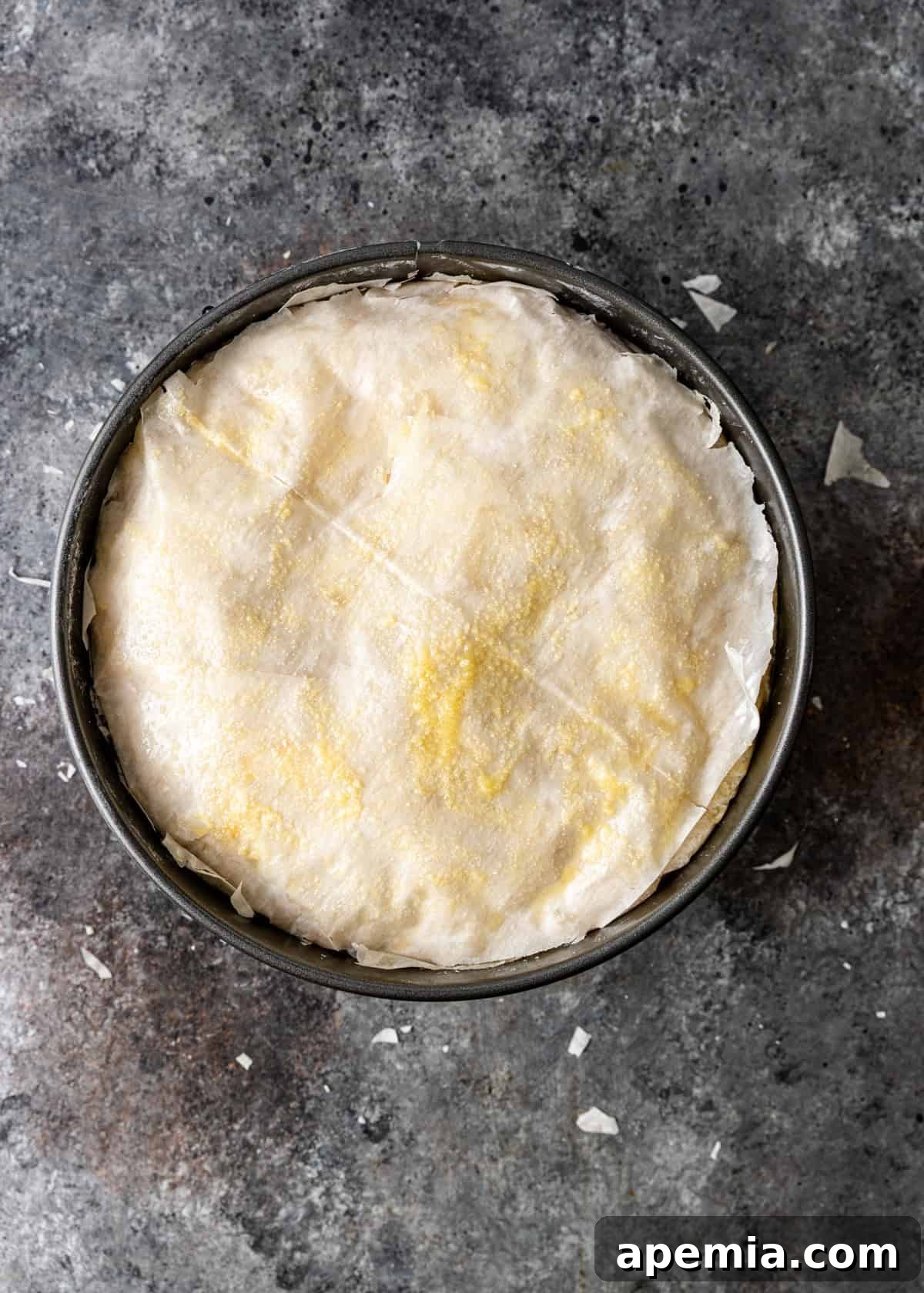 Overhead process shot of a fully assembled phyllo custard pie, meticulously layered and buttered, ready to be baked to golden perfection.