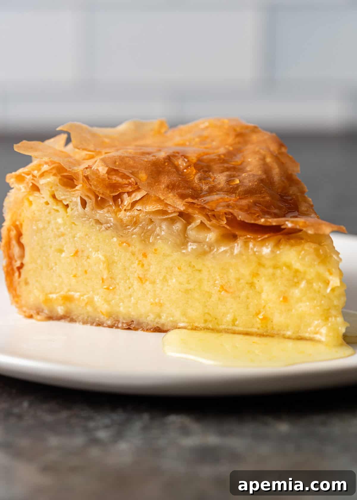 Side view of a perfectly presented slice of phyllo custard pie, highlighting its smooth, creamy filling and distinct layers of golden-brown pastry.