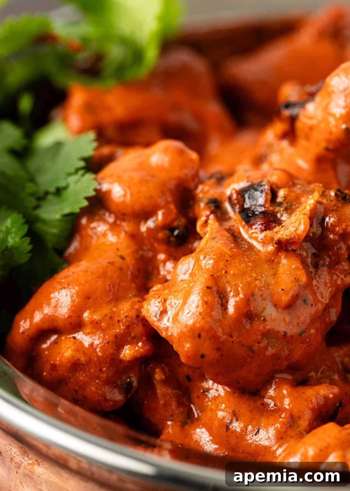 Close-up shot of a single serving of the rich ruby chicken curry with a scoop of rice, highlighting the sauce's texture.