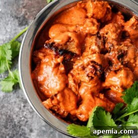 A final presentation of Dishoom's Ruby Chicken Curry, in a bowl with rice and garnish.