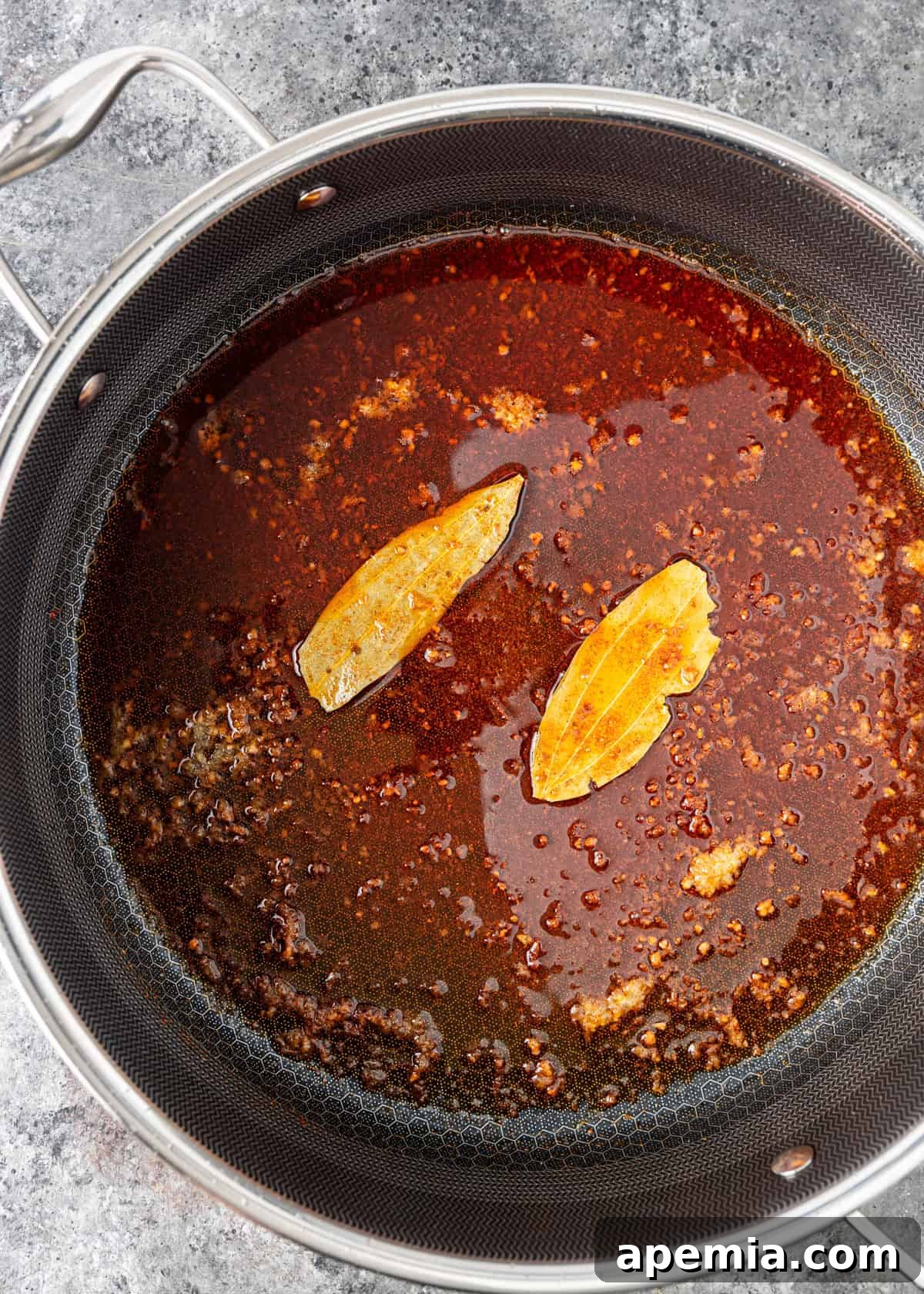 Process shot: A large skillet on the stove, beginning to cook the aromatic base for the ruby chicken sauce.