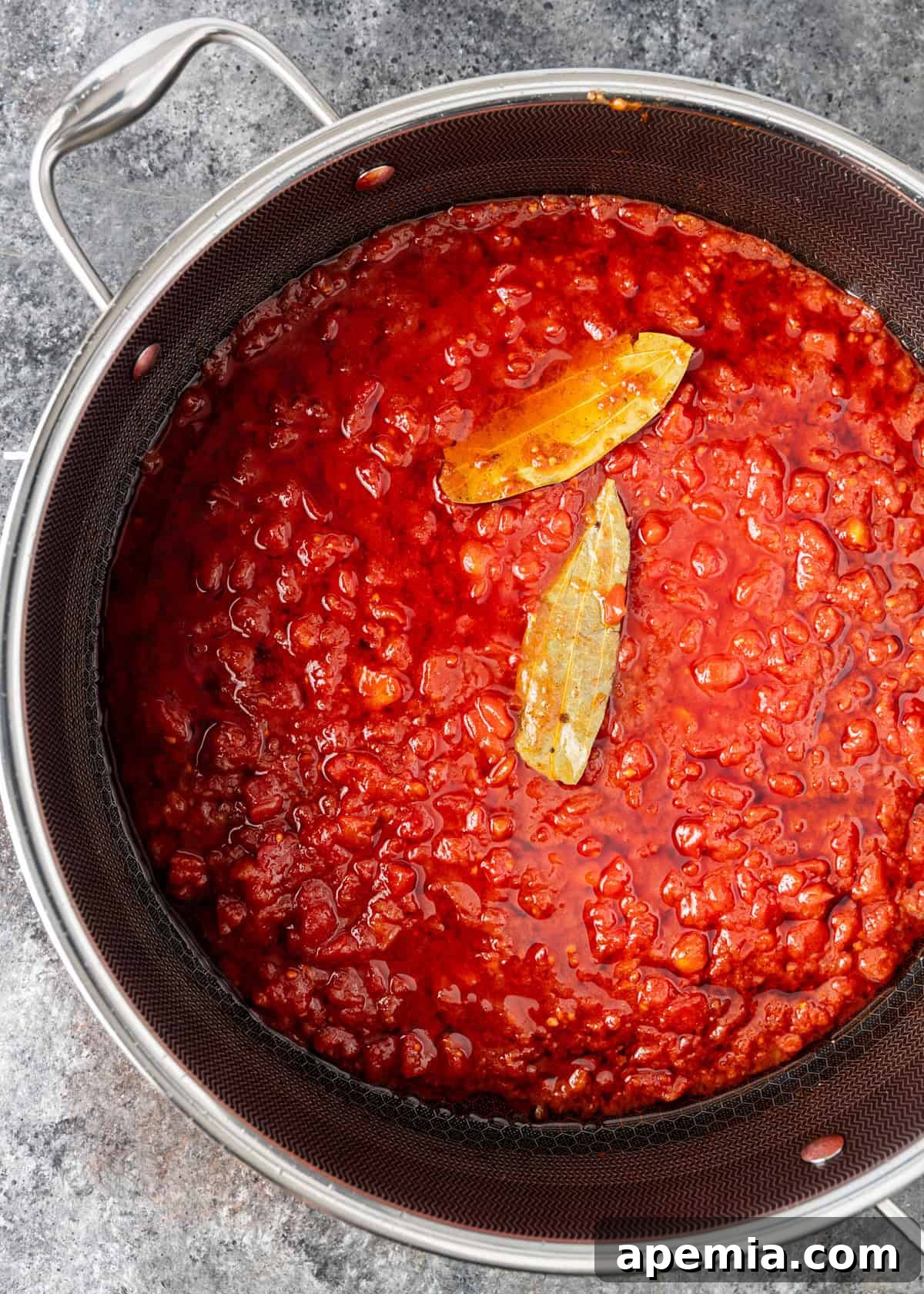 Process shot: The ruby chicken sauce gently simmering in a skillet, with bay leaves infusing their fragrance.