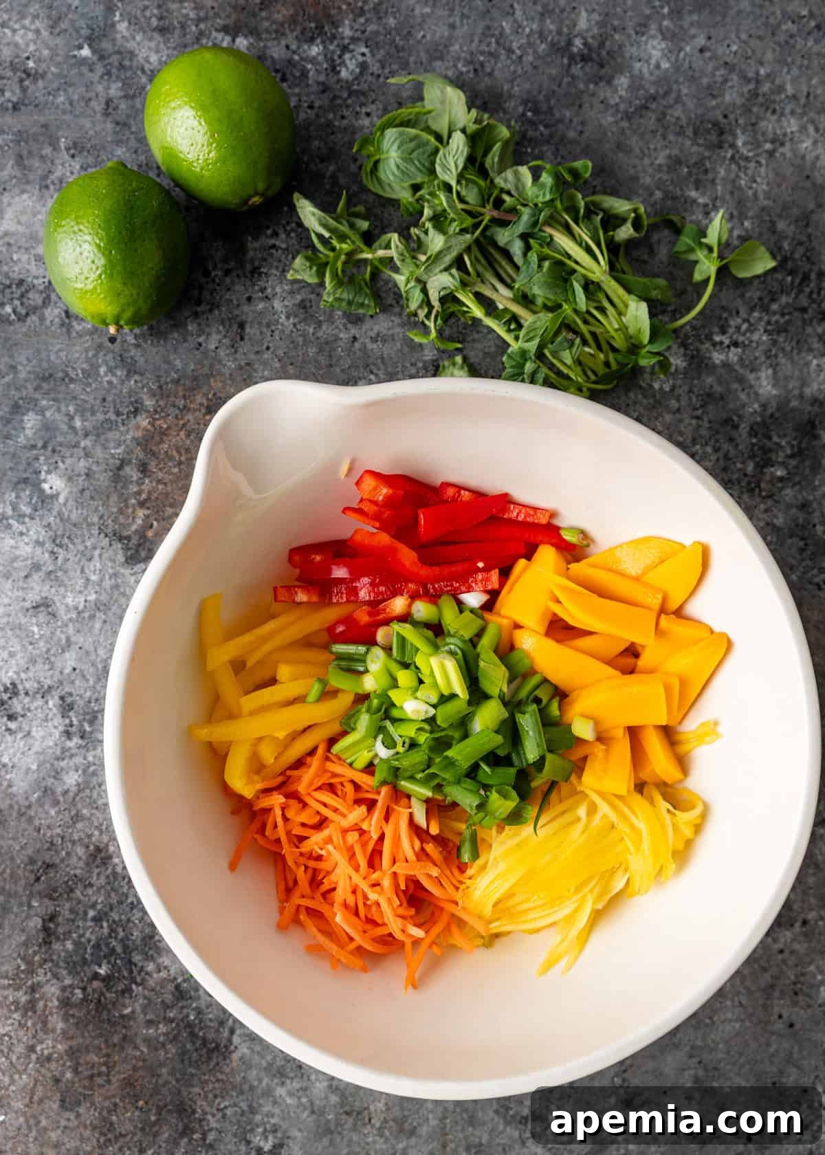 Overhead view of fresh veggies and fruit prepared in a white bowl