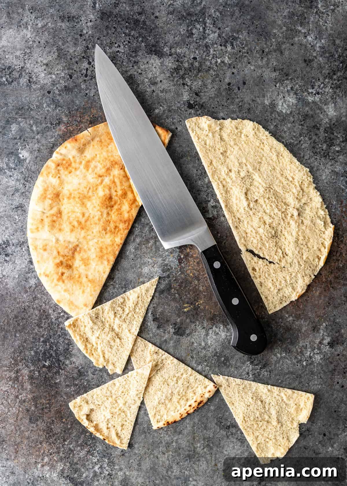 overhead: an uncooked pita sliced into triangles with a large knife
