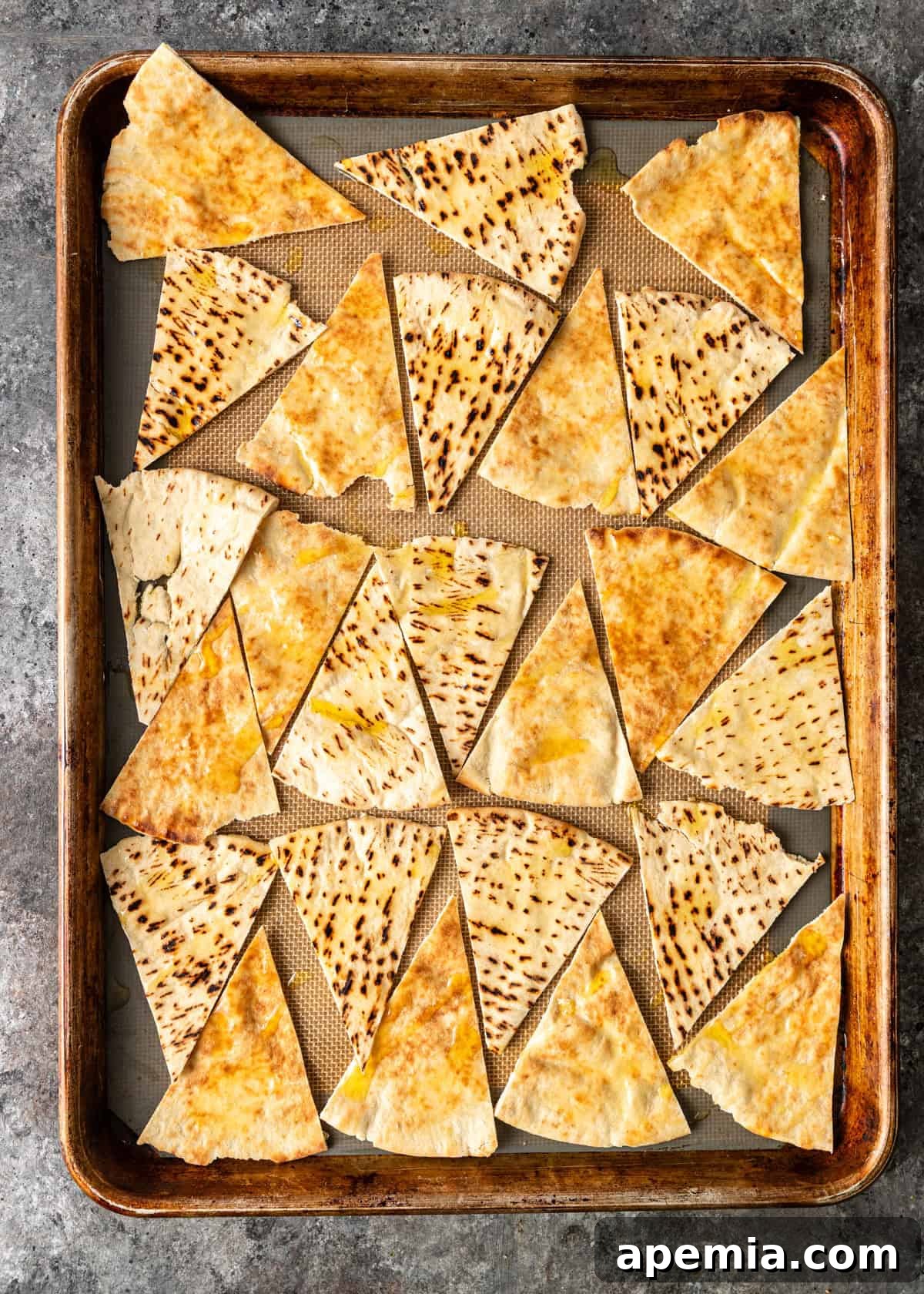overhead: pita triangles brushed with oil on a baking sheet