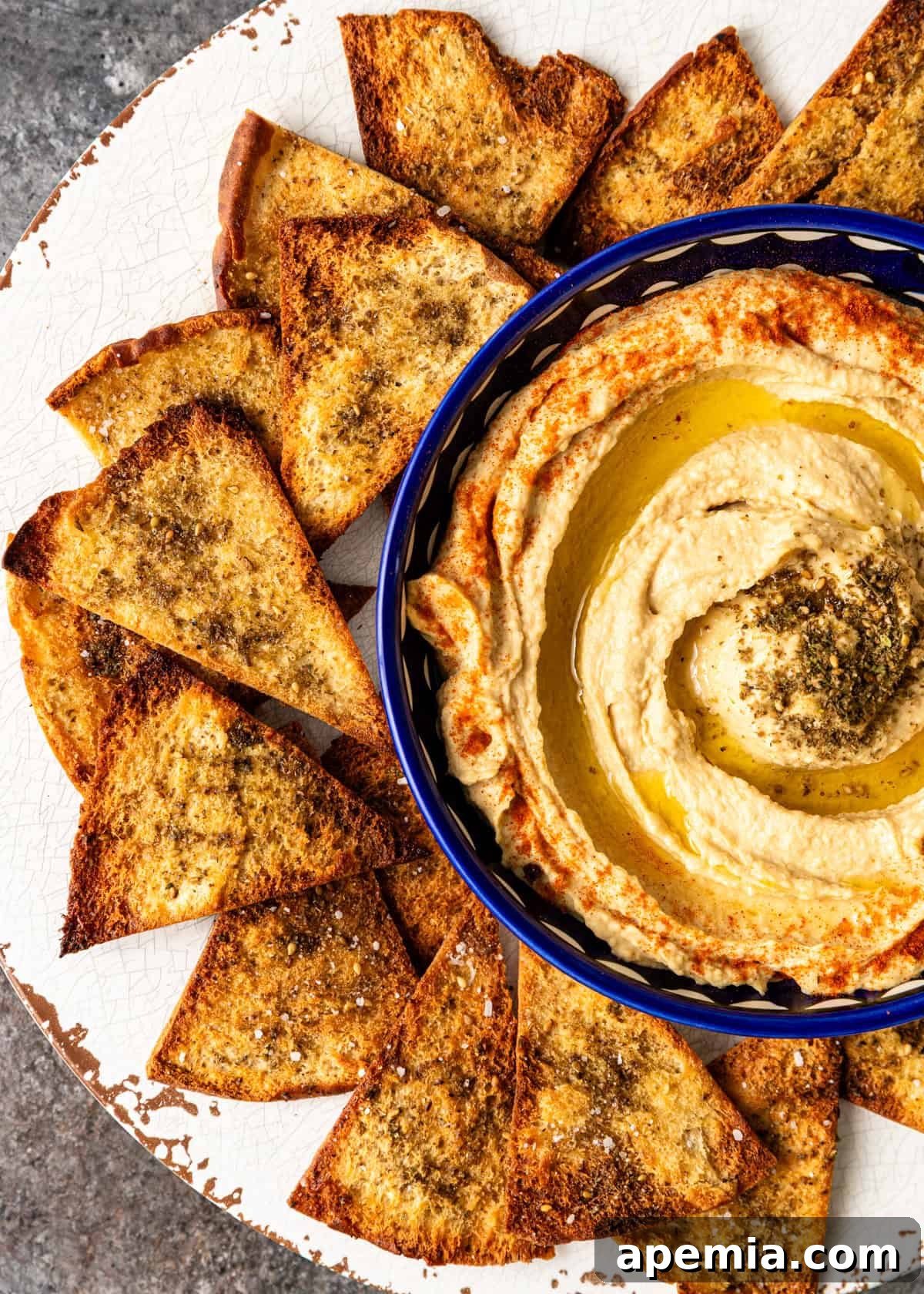 overhead: homemade pita chips surrounding a blue bowl of hummus