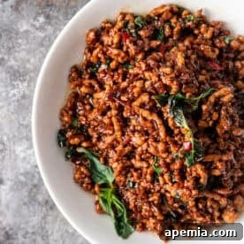 A vibrant bowl of Thai Pad Kra Pao with perfectly cooked ground pork and fresh basil.