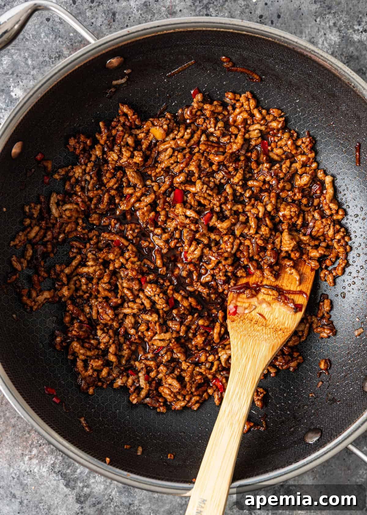 overhead process shot: browned pork and aromatics for pad kra pao in a wok