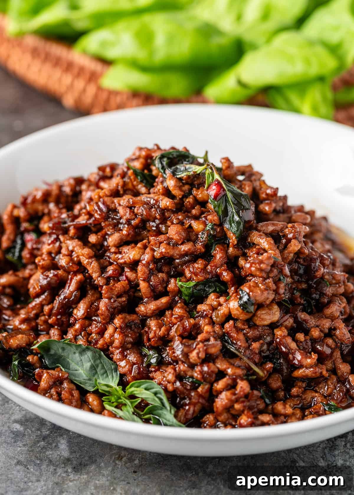 closeup: a white serving dish of pad kra pao with basil on top