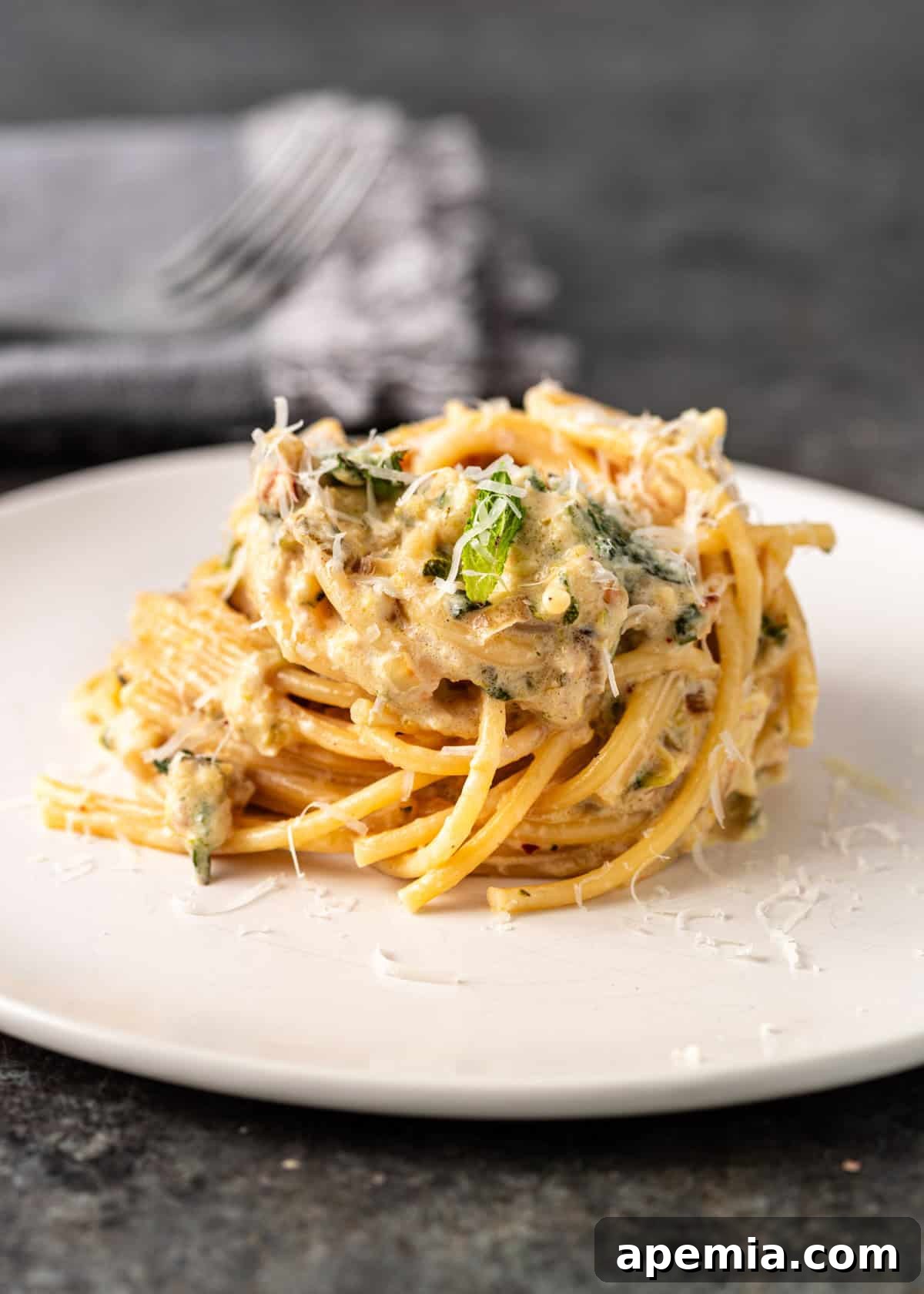 Side view closeup: a plated serving of lemon zucchini pasta, garnished with grated Parmesan cheese and fresh mint, ready to be enjoyed