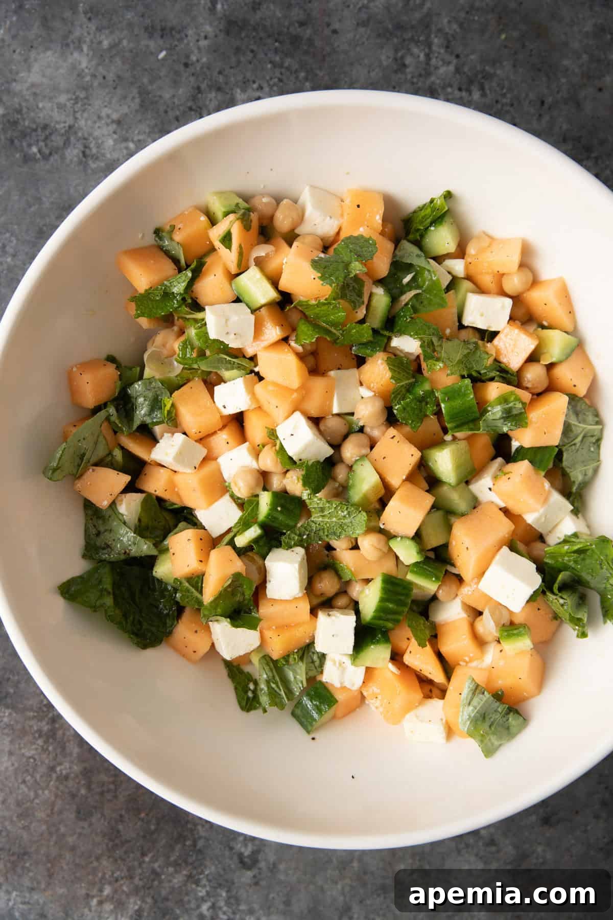 overhead: cantaloupe salad ingredients in a large bowl before mixing, close-up