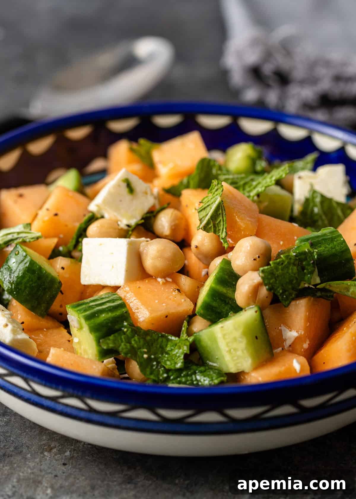 side view closeup: cantaloupe salad in a bowl with cucumbers, chickpeas, and feta
