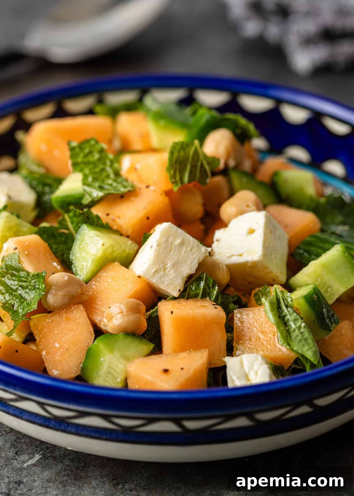 closeup: melon salad with fresh herbs, chickpeas, cucumbers, and feta, beautifully arranged