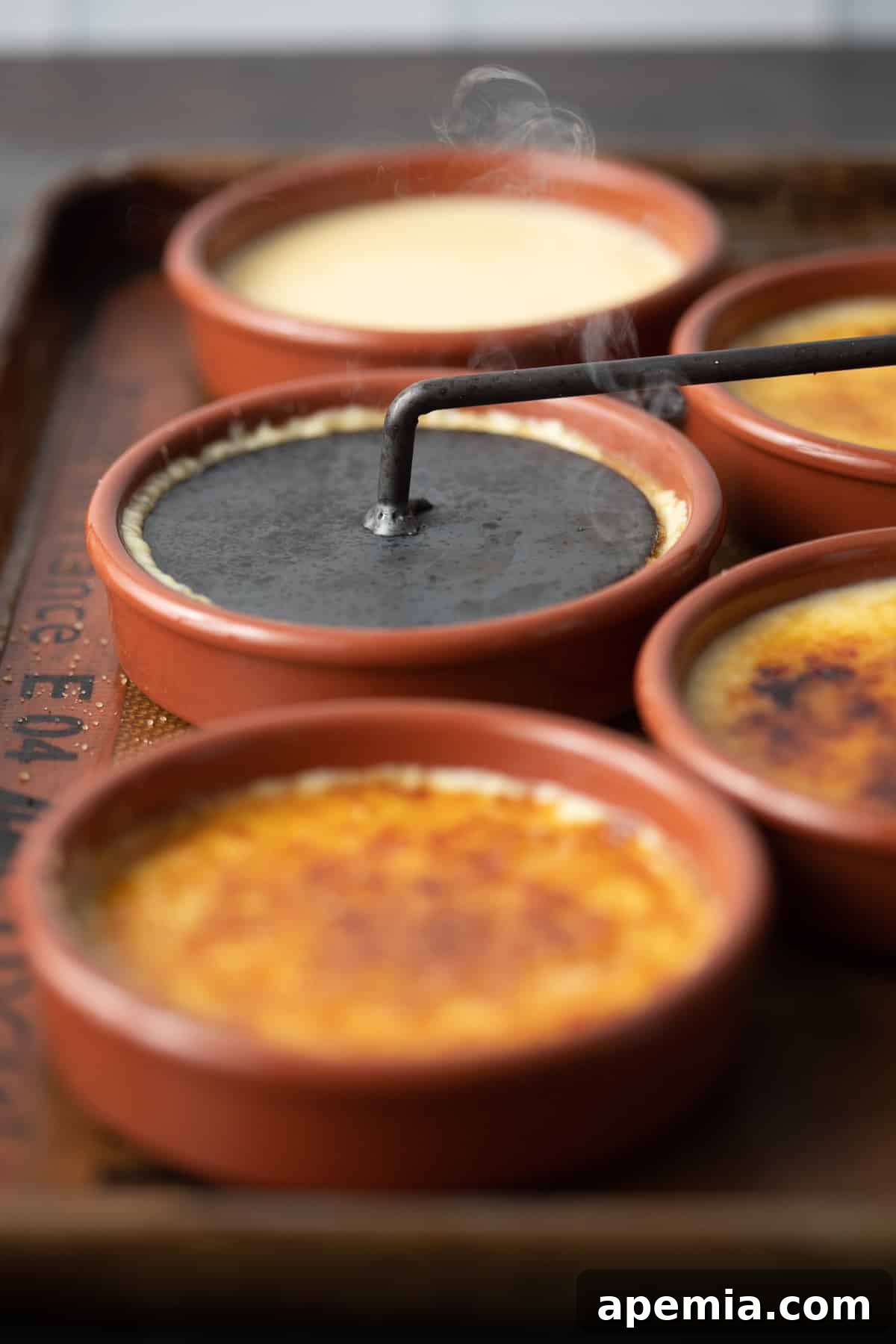 side view: catalana iron touching the top of the Spanish creme brulee to caramelize it