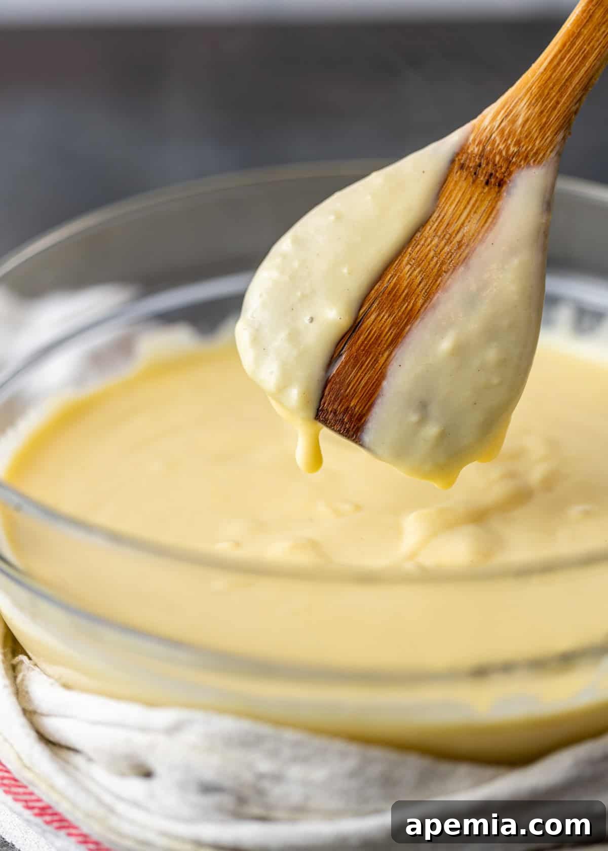 side view: a wooden spoon stirring crema catalana batter