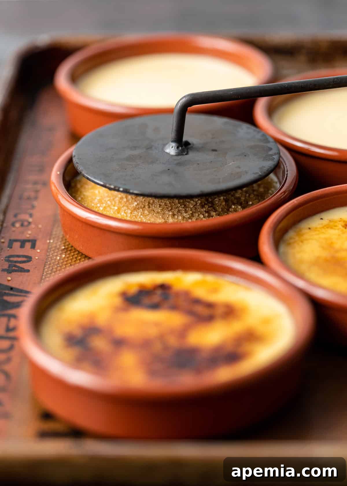 side view: using a catalana iron to caramelize the top of my crema catalana recipe