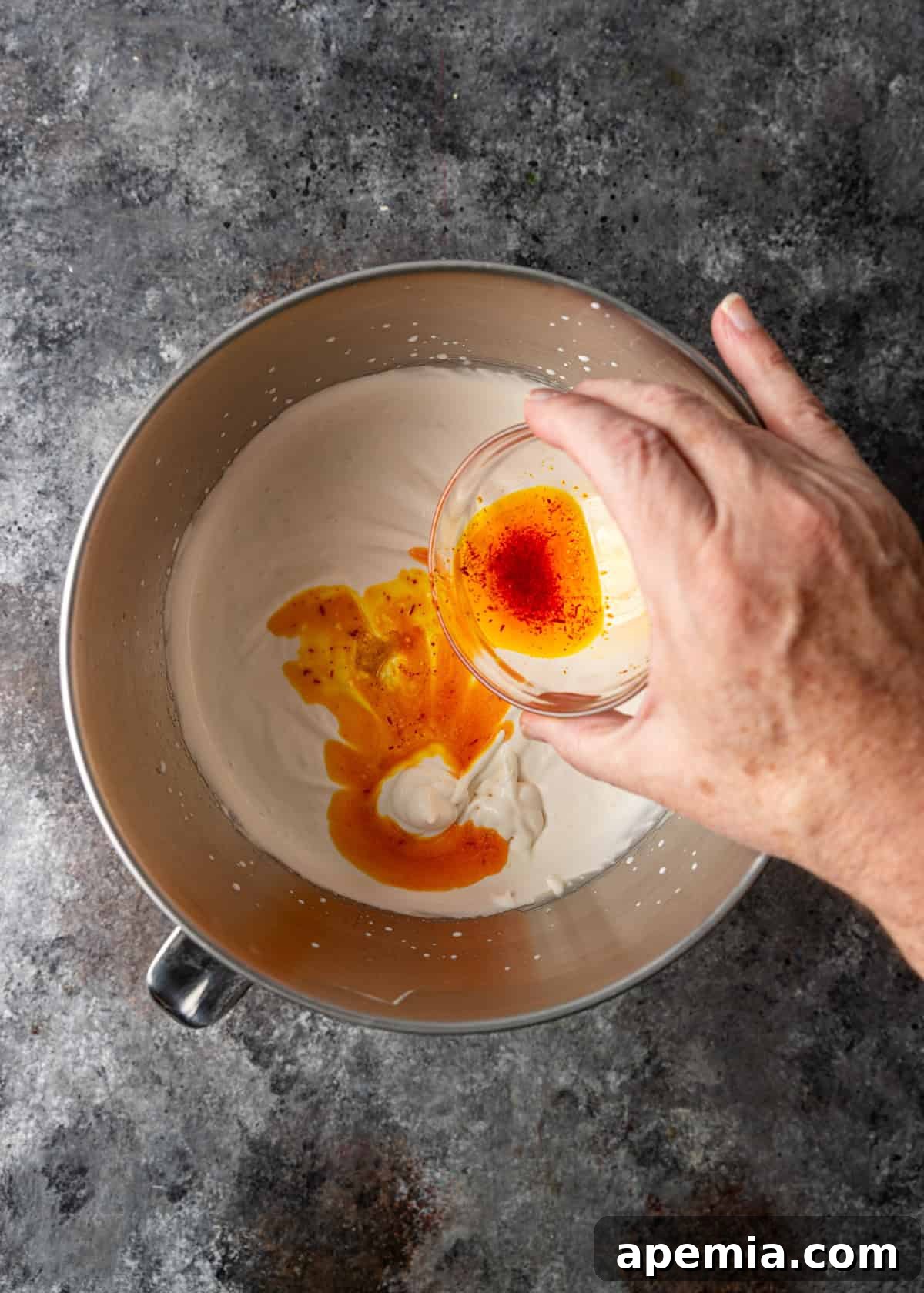 Process shot: Saffron and rose water mixture being carefully added to the creamy milk base, infusing flavor.