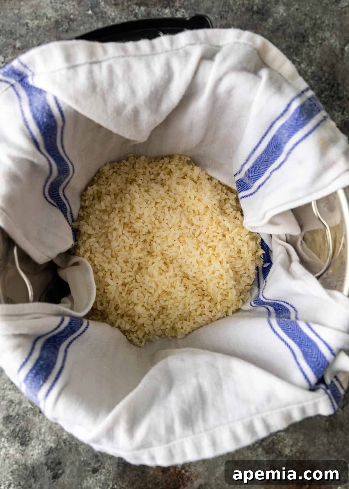 Overhead view of glutinous rice cooking in an Instant Pot, lined with a damp kitchen towel to prevent sticking