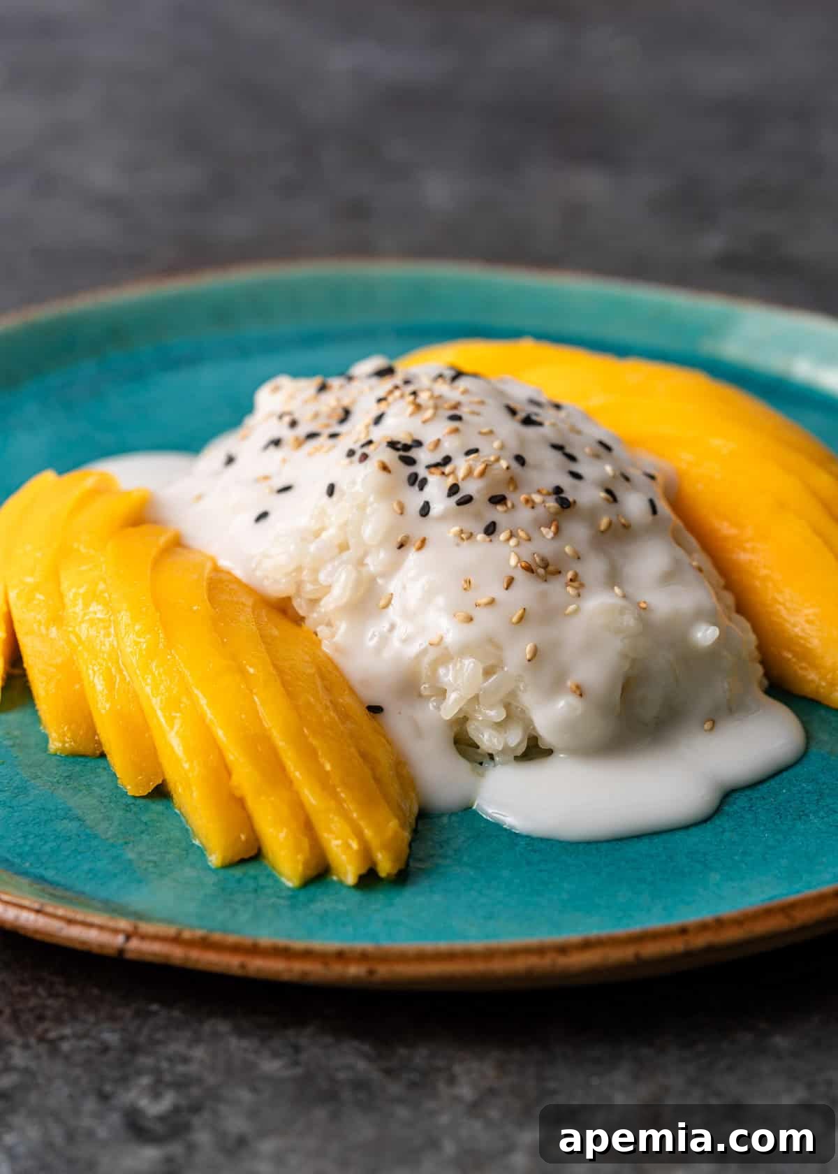 Extreme closeup of mango sticky rice, showcasing the glistening coconut sauce and sprinkled sesame seeds