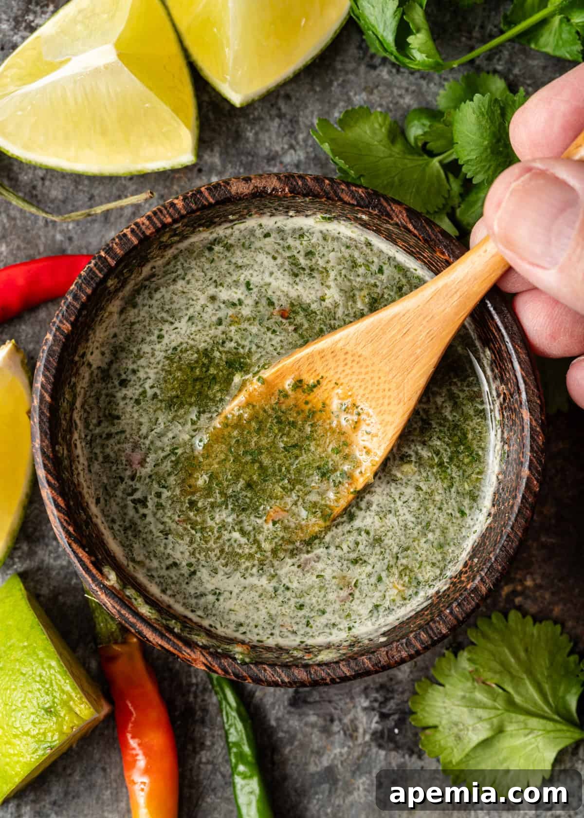 overhead: a hand stirring a small bowl of fresh Thai dipping sauce with a wooden spoon