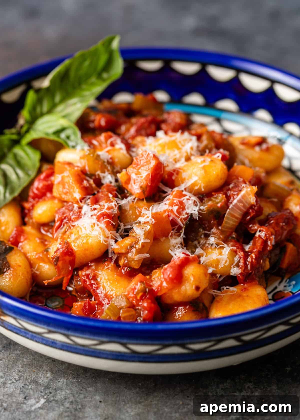 closeup side view: cooked sugo finto in bowl on countertop sprinkled with vegan parmesan