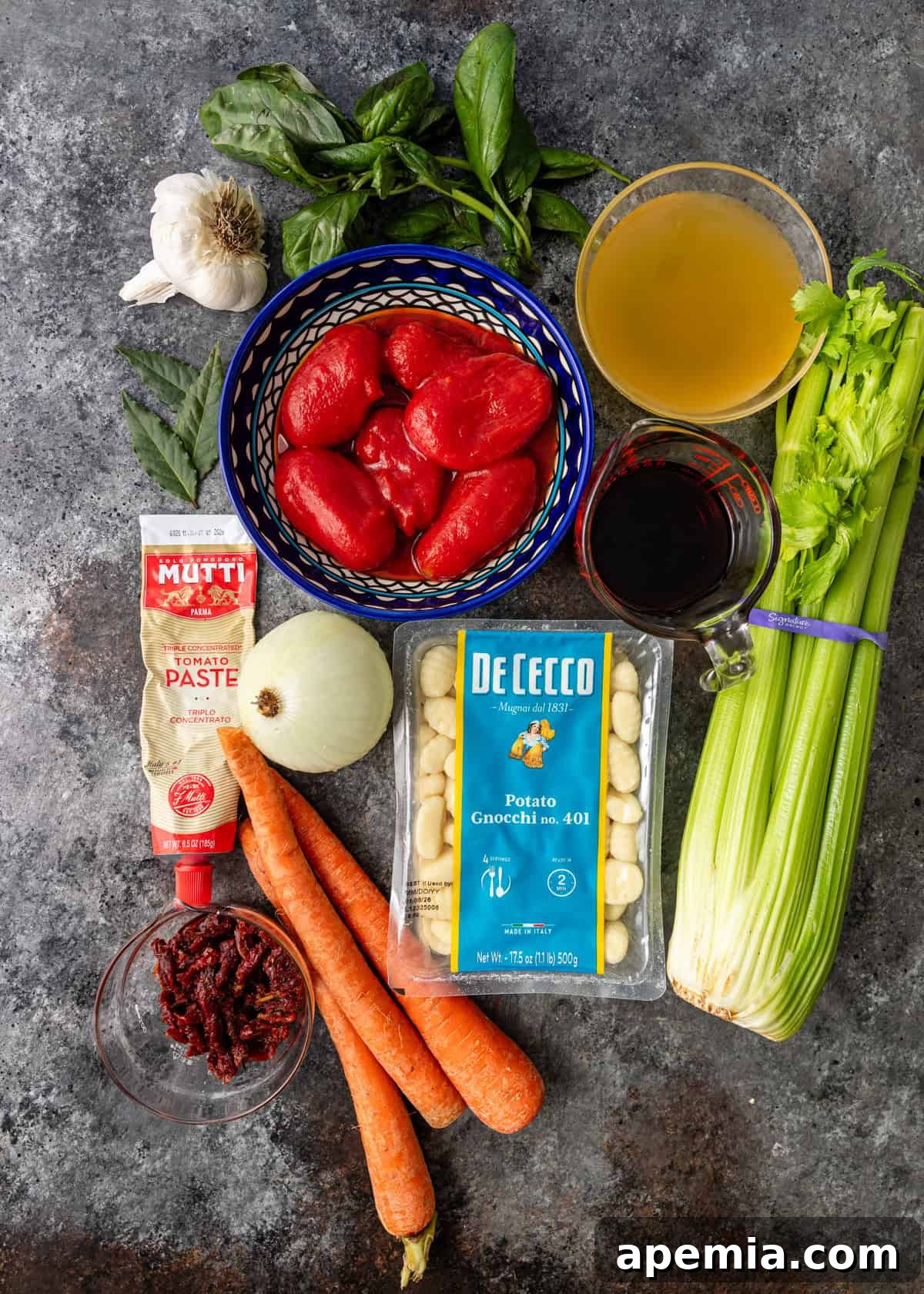 overhead: all fresh and canned ingredients needed to make the sugo finto recipe laid out on a white surface