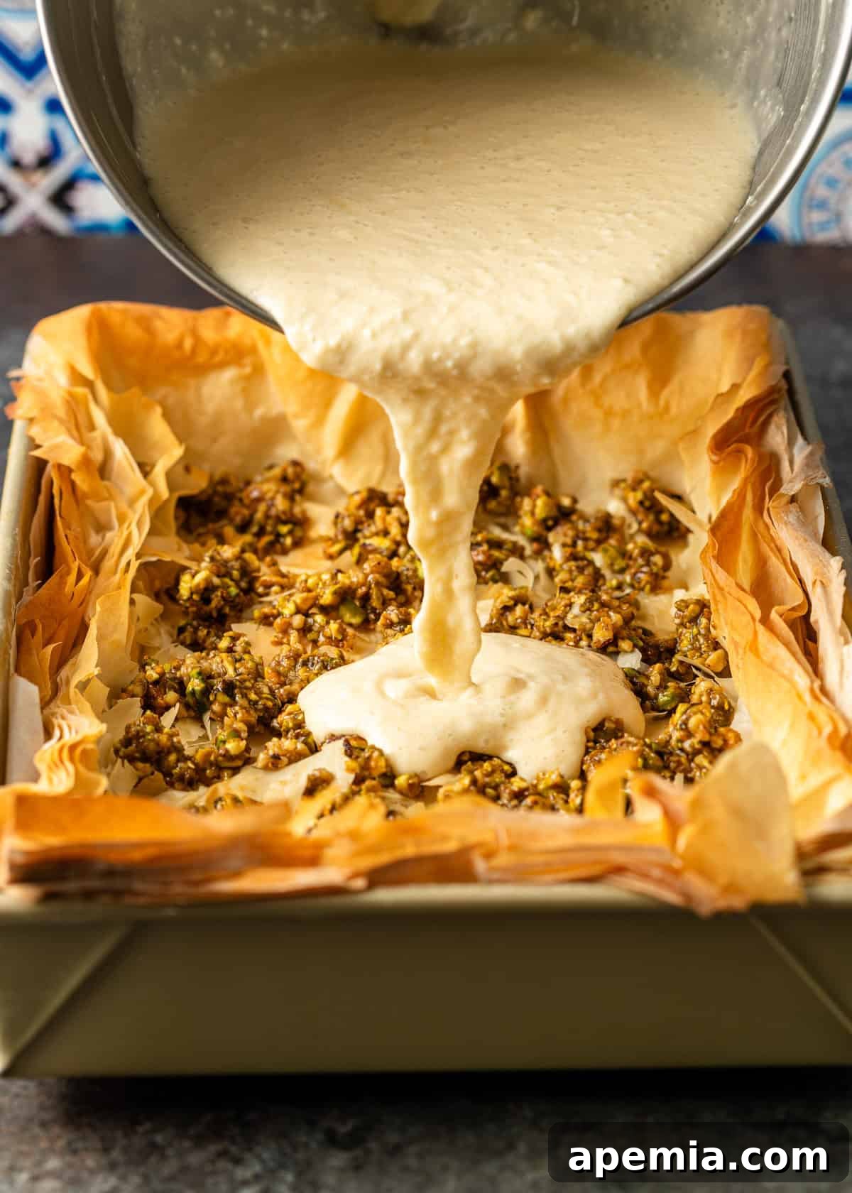 overhead process shot: mixing bowl over top pouring cheesecake mixture into baked baklava