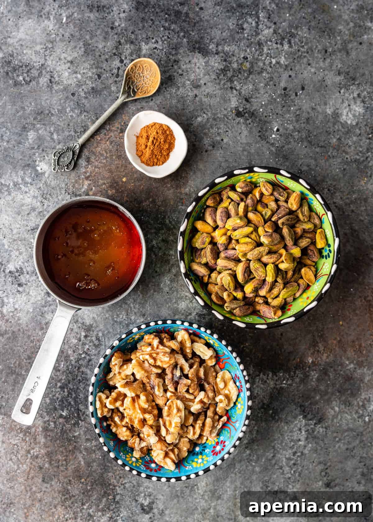 Overhead process shot: all the essential ingredients laid out for Baklava Stuffed Dates, including Medjool dates, walnuts, pistachios, cinnamon, and honey.