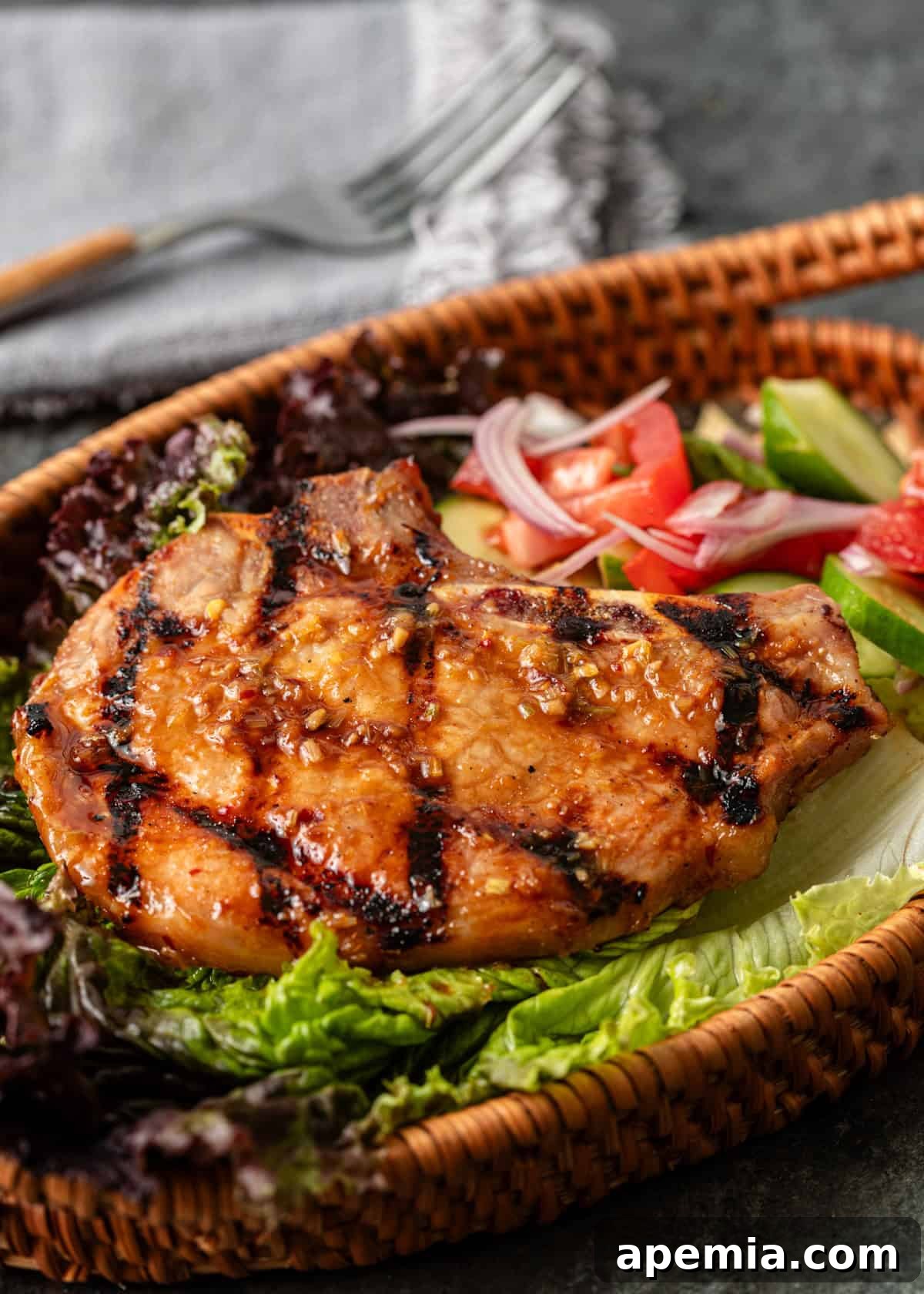 Overhead close-up of Sườn Nướng (Vietnamese Pork Chops) beautifully arranged over fresh salad in a rustic wicker serving basket, inviting diners to enjoy.