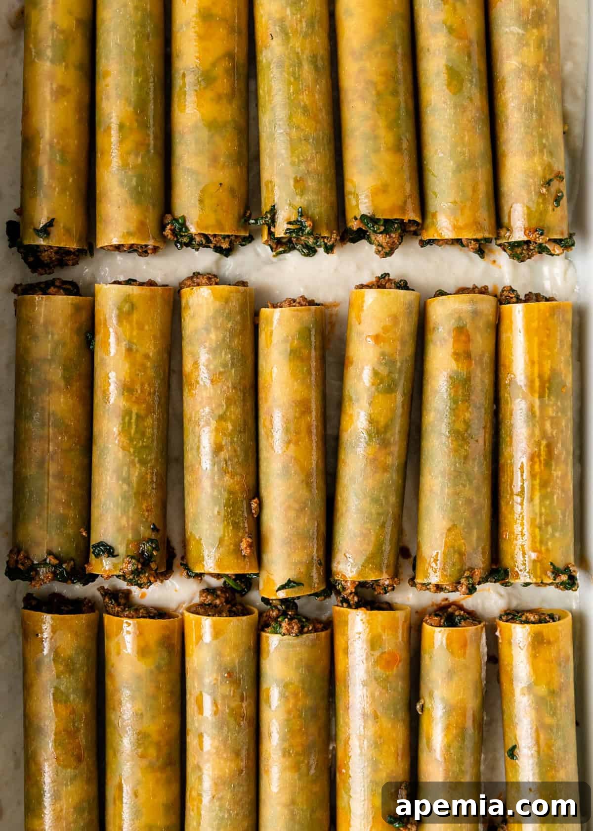 overhead process shot: cannelloni shell with the prepared meat filling on sheet pan
