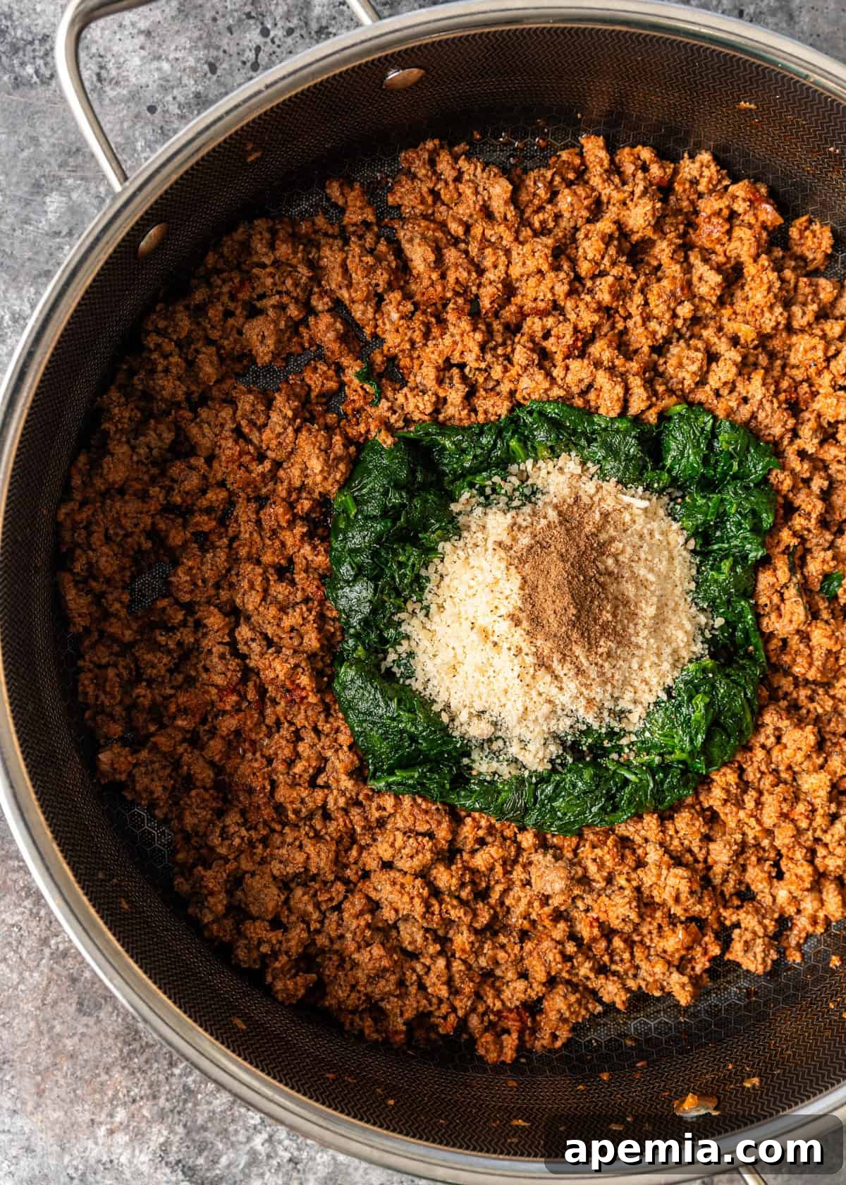 overhead process shot: beef mixture in skilled with spinach and seasonings