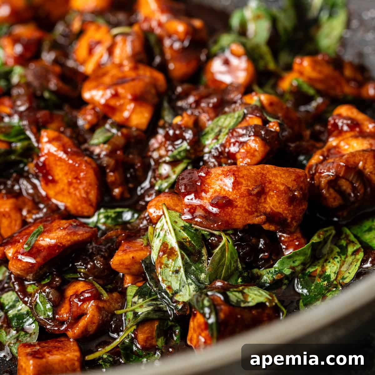 Closeup of vibrant Thai Basil Chicken stir-fry on a plate, garnished with fresh basil leaves, ready to be enjoyed.