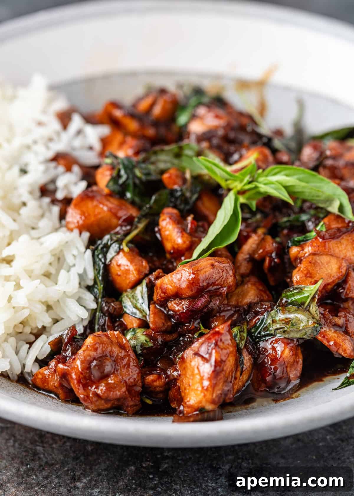 Overhead shot of Thai Basil Chicken served with jasmine rice on a white plate, highlighting the vibrant colors and textures of the dish.