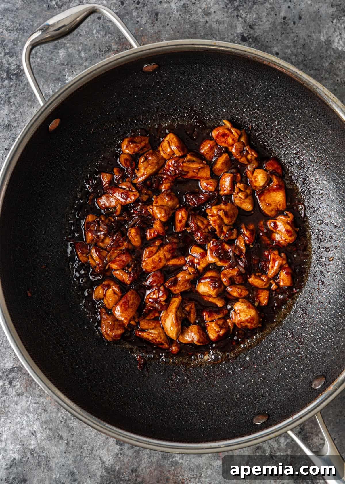 Process shot: The savory stir-fry sauce being poured over the cooked chicken and aromatics in the wok, coating everything evenly.