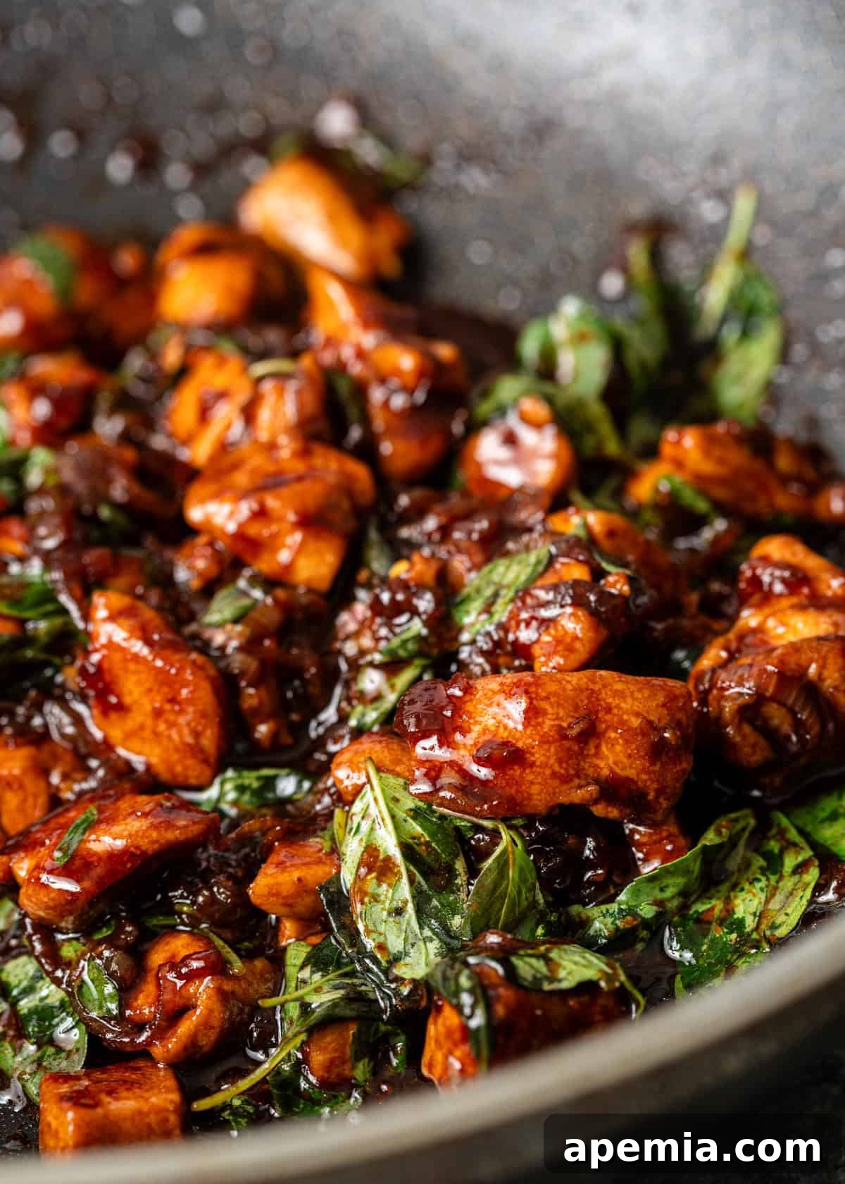 Side view of a serving of Thai Basil Chicken with white rice, showcasing the succulent chicken and fresh basil.