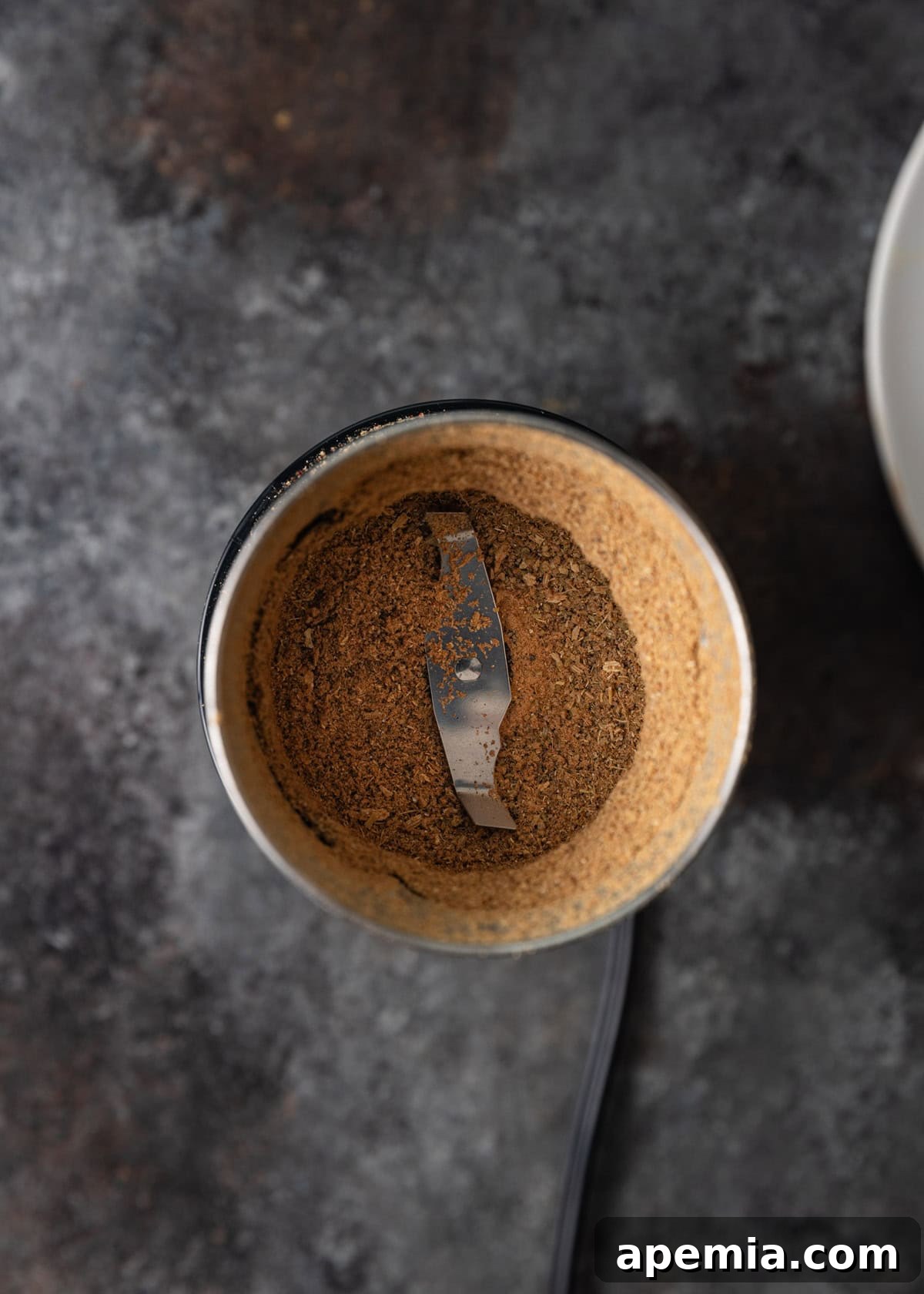 overhead process shot: ground up spices in silver spice grinder