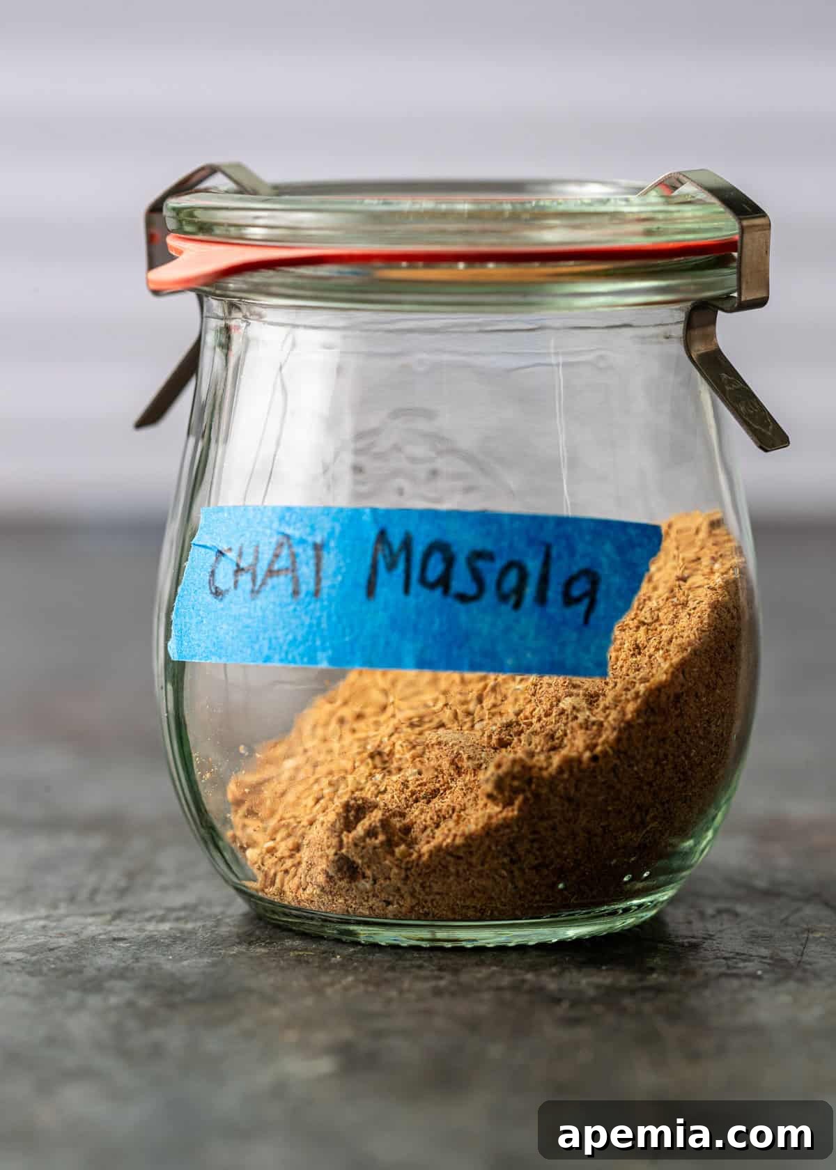 closeup side view: chai masala ground up spices in clear jar