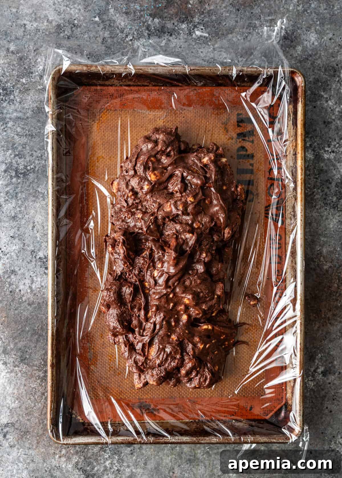overhead process shot: chocolate salami spread on plastic wrap on sheet pan