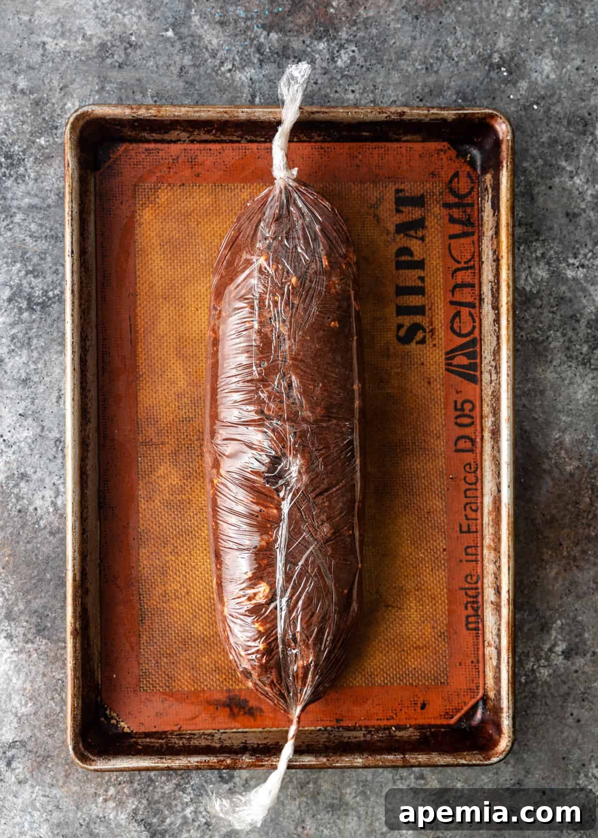 overhead process shot: chocolate salami rolled in plastic wrap on sheet pan