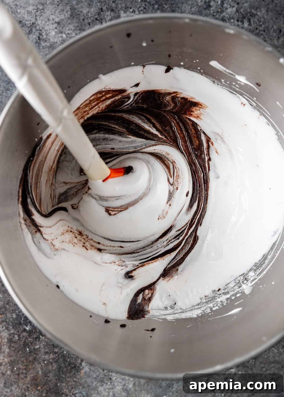 overhead process shot: adding the chocolate mixture to the egg white meringue mixture in mixing bowl