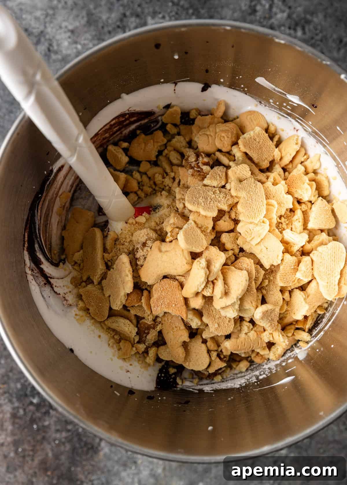 overhead process shot: adding the crushed cookies and walnuts to chocolate mixture and egg white meringue mixture in mixing bowl