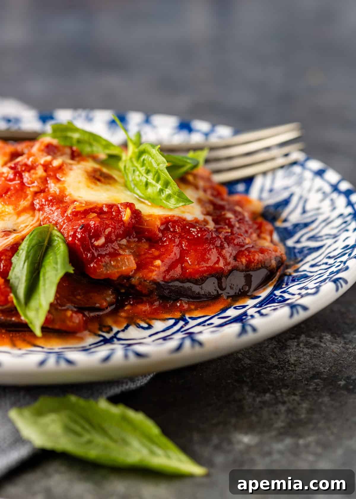 closeup side view: parmigiana on blue and white plate with basil on top