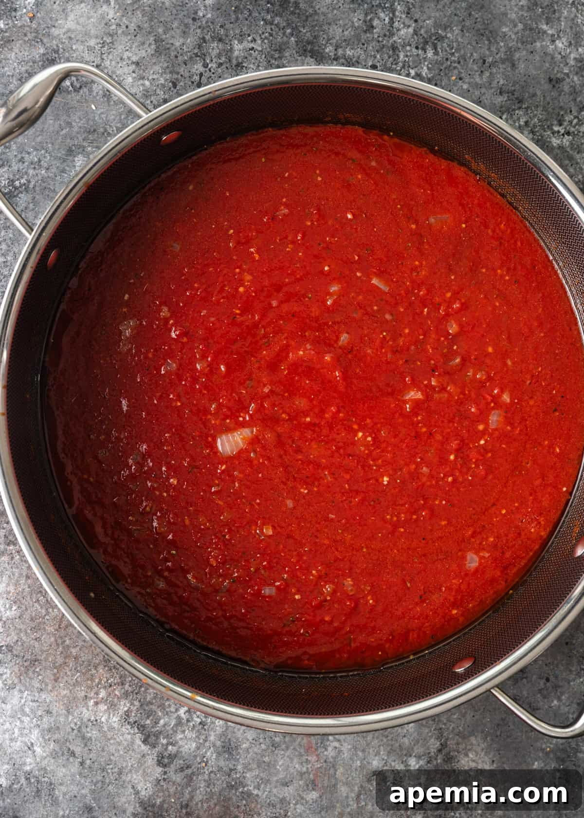 overhead process shot: crushed tomatoes and tomato paste added to deep frying pan
